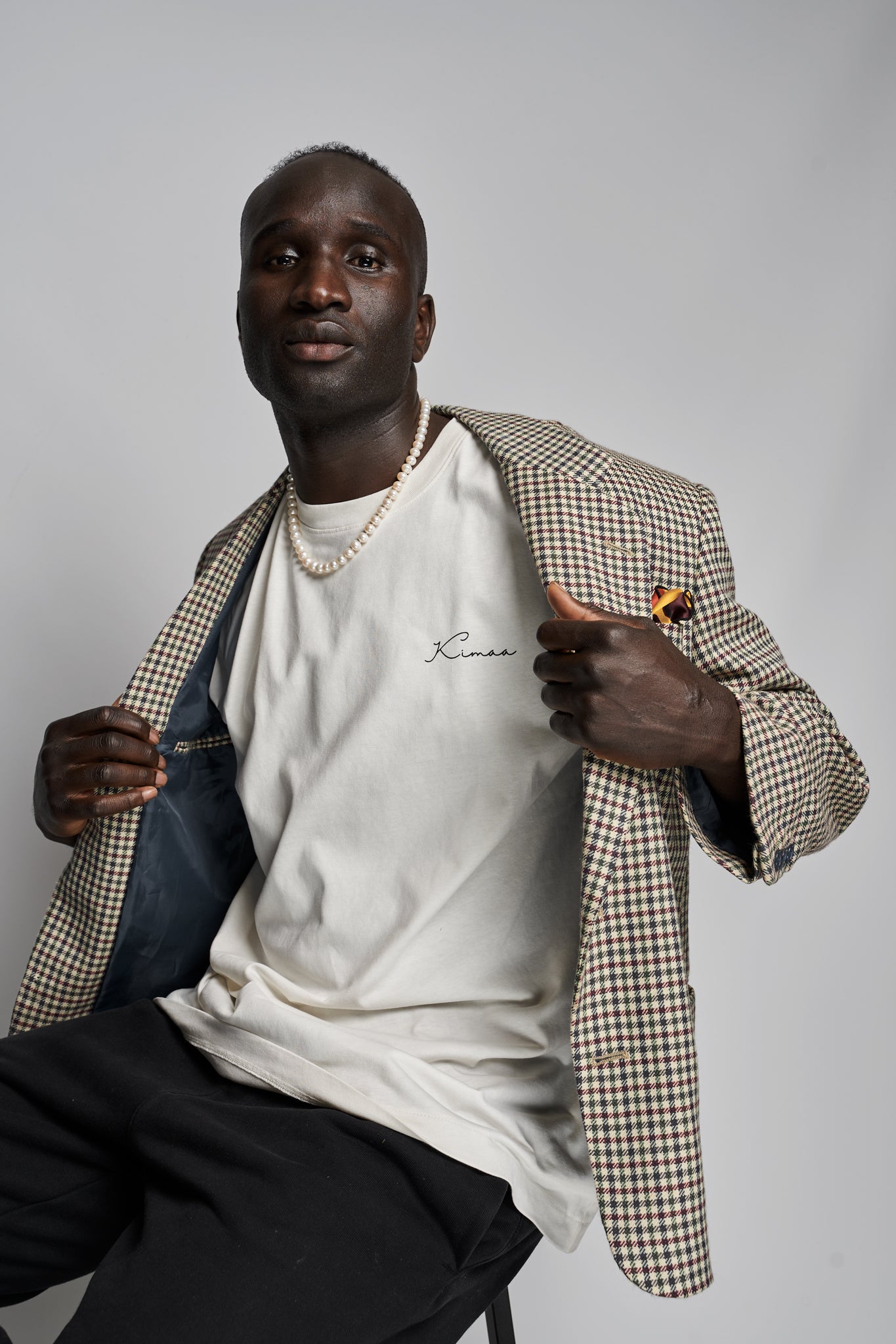 Model layering Kimaa’s beige Bankoo T-shirt with a patterned coat — Afro-Nordic aesthetic with warmth.