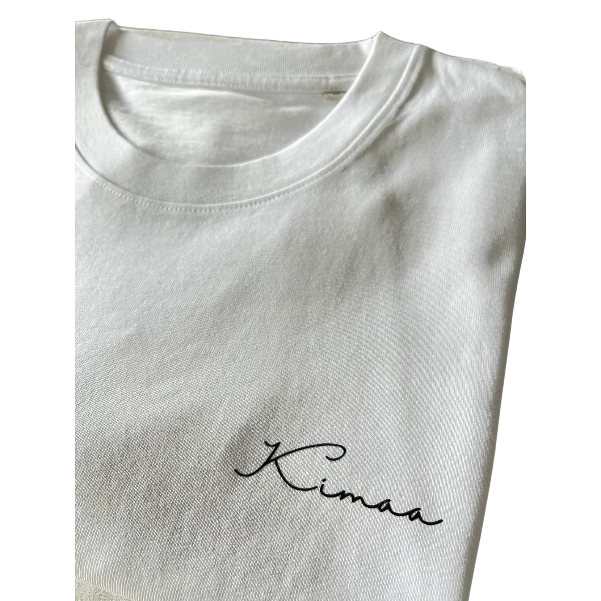 Kimaa logo closeup on chest of Senumaa white T-shirt — sustainable, subtle branding.